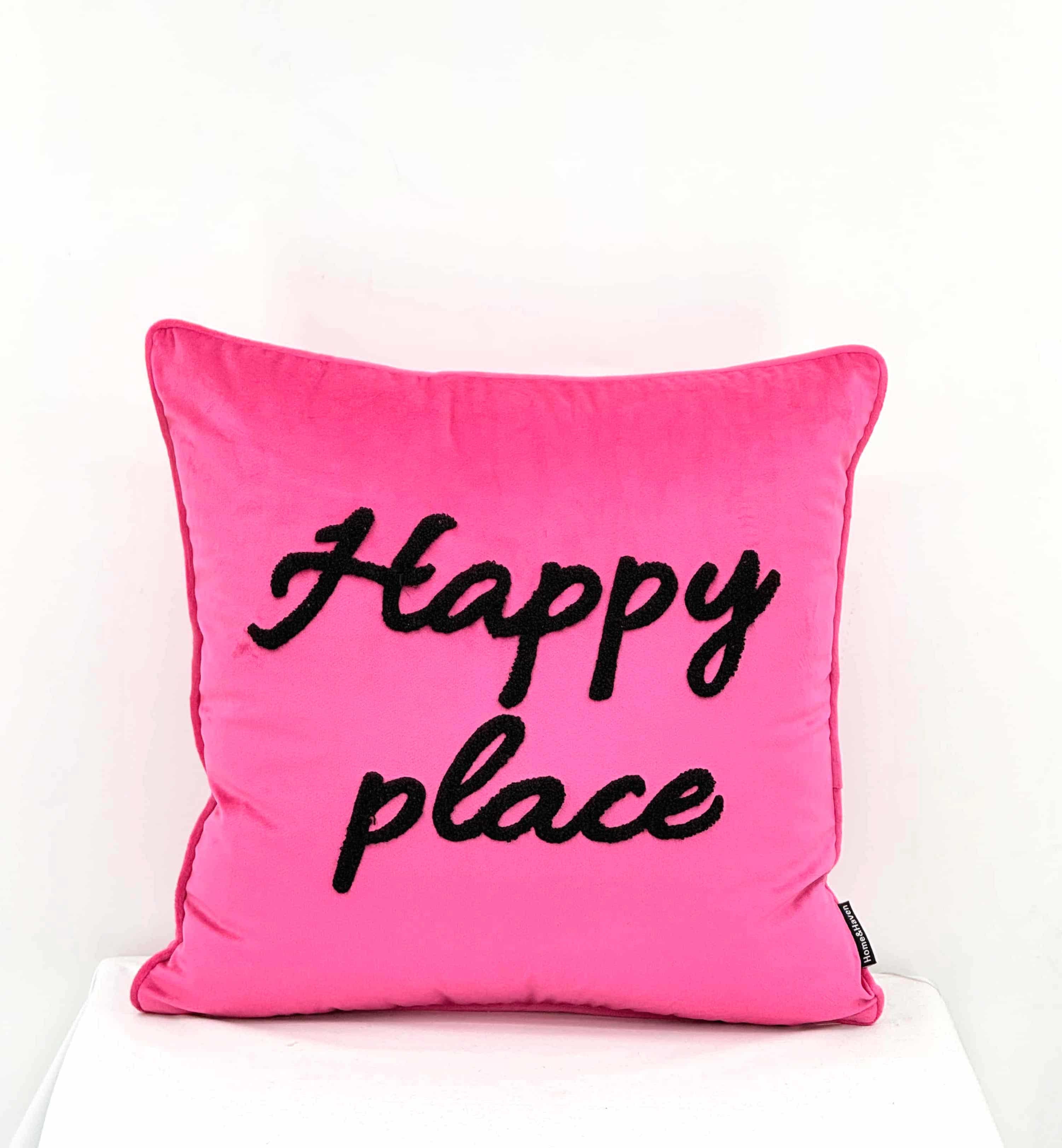 A square hot pink throw pillow with the words 'Happy place' embroidered in black script across the front, displayed against a clean white background.