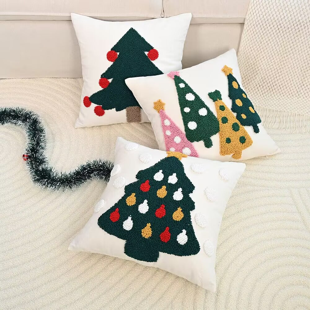 Three decorative pillows with Christmas tree designs on a couch.