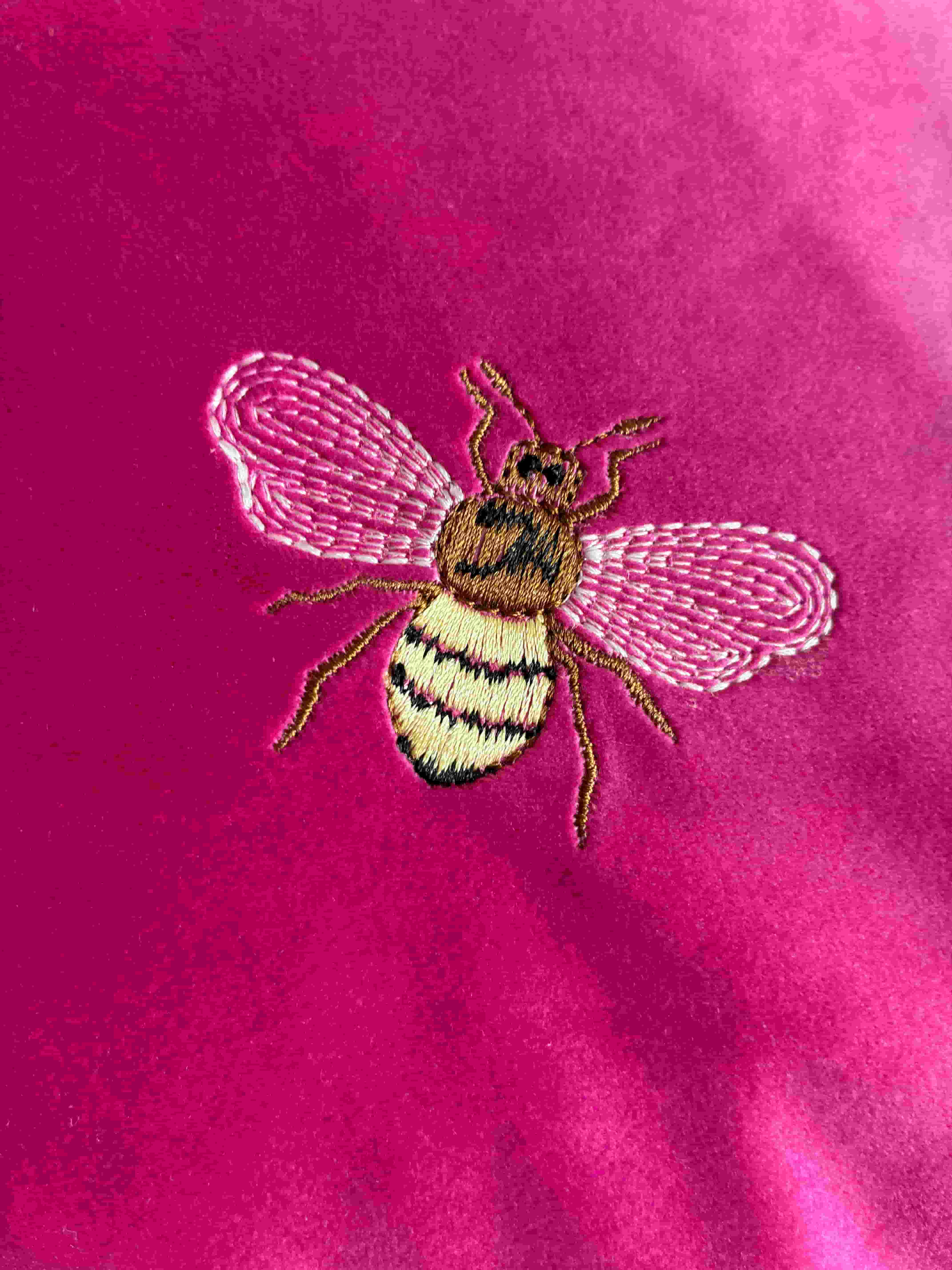 Close up detail of handcrafted honey bee embroidery on pink velvet cushion cover
