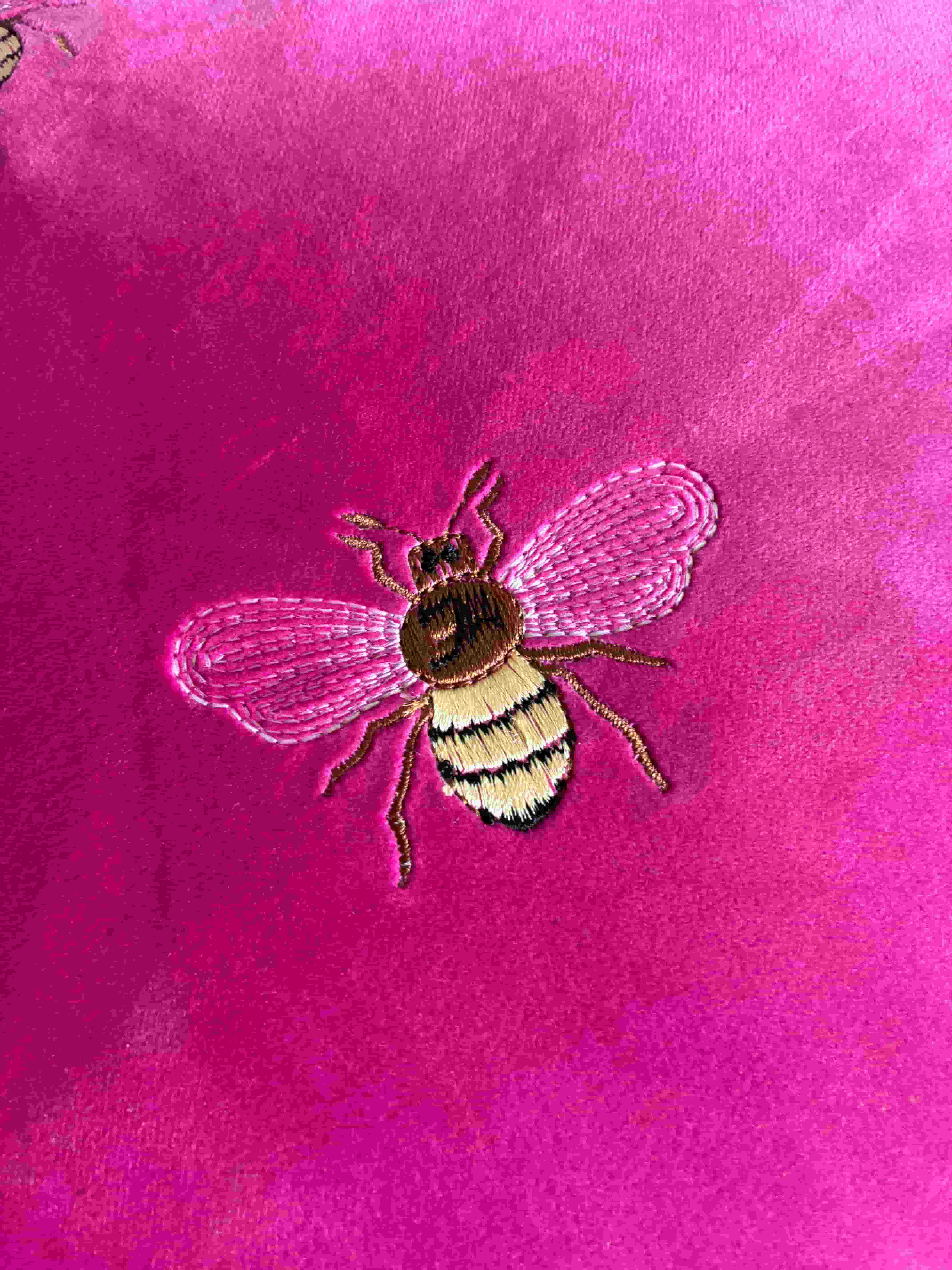 Detailed honey bee embroidery stitching on luxury pink velvet pillow cover