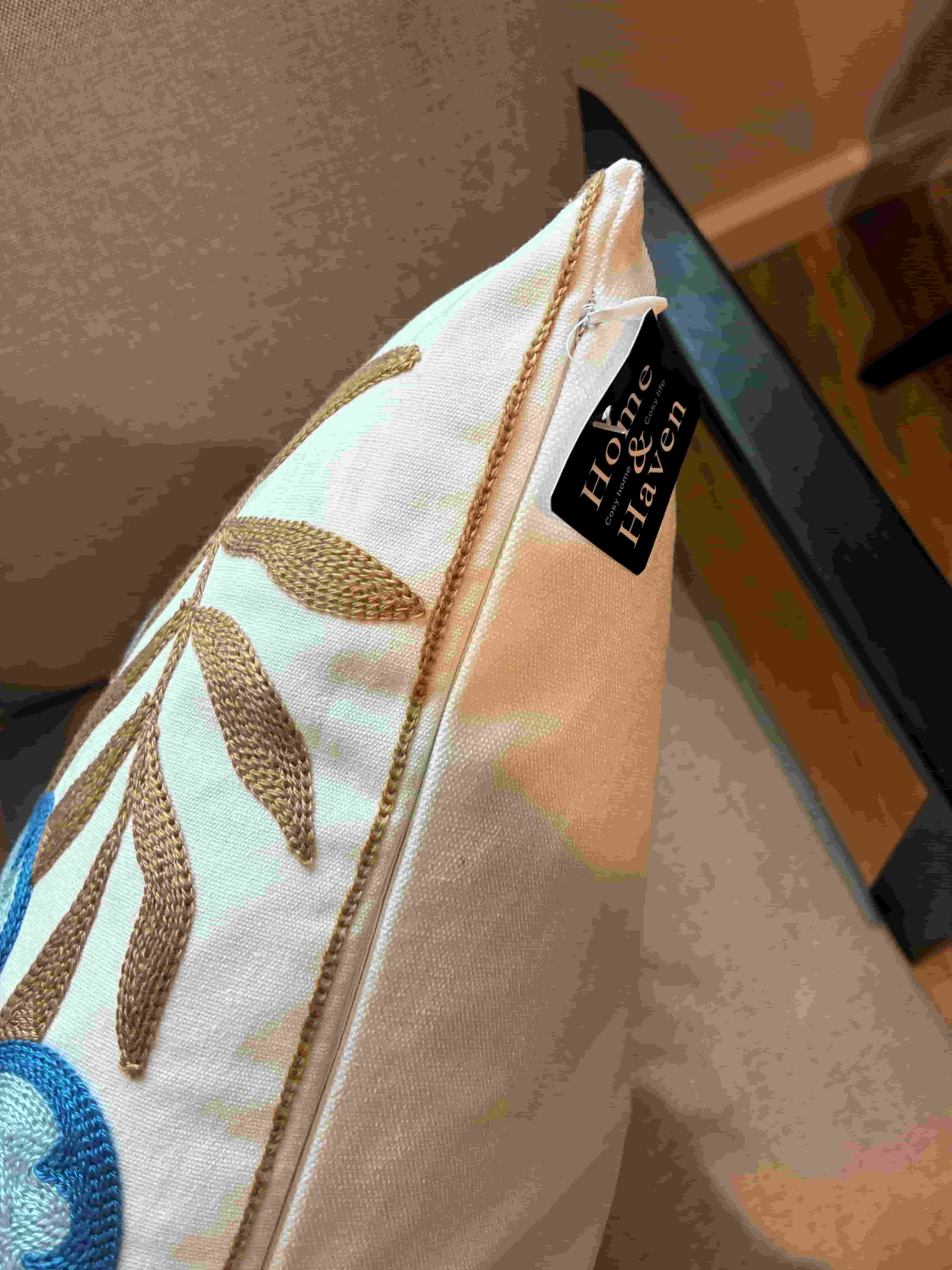 Side view of a floral embroidered cushion cover showing a smooth zipper closure, subtle contrast piping, and a black Home & Haven brand tag.