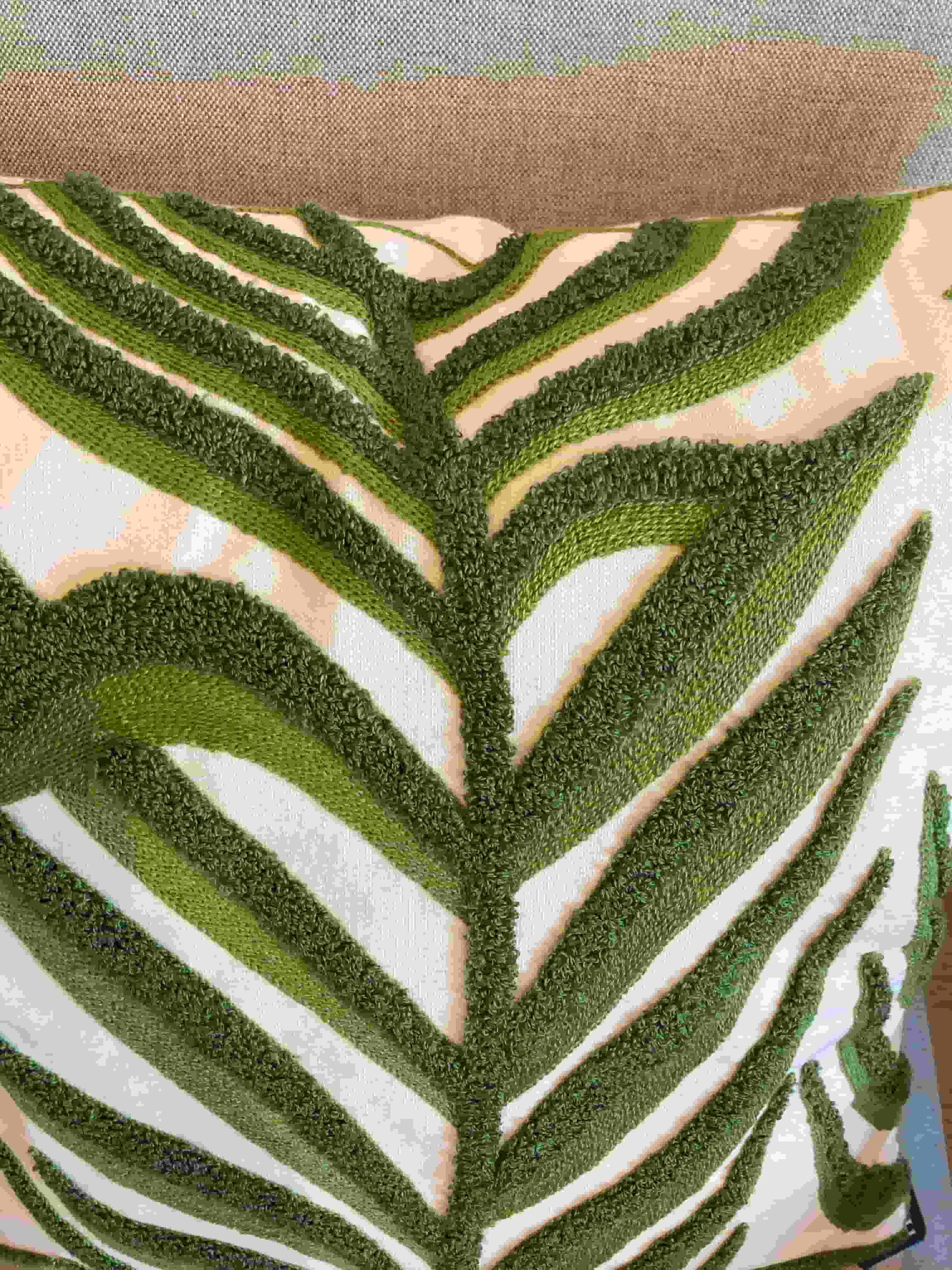Close-up of a textured green leaf design on a fabric surface.