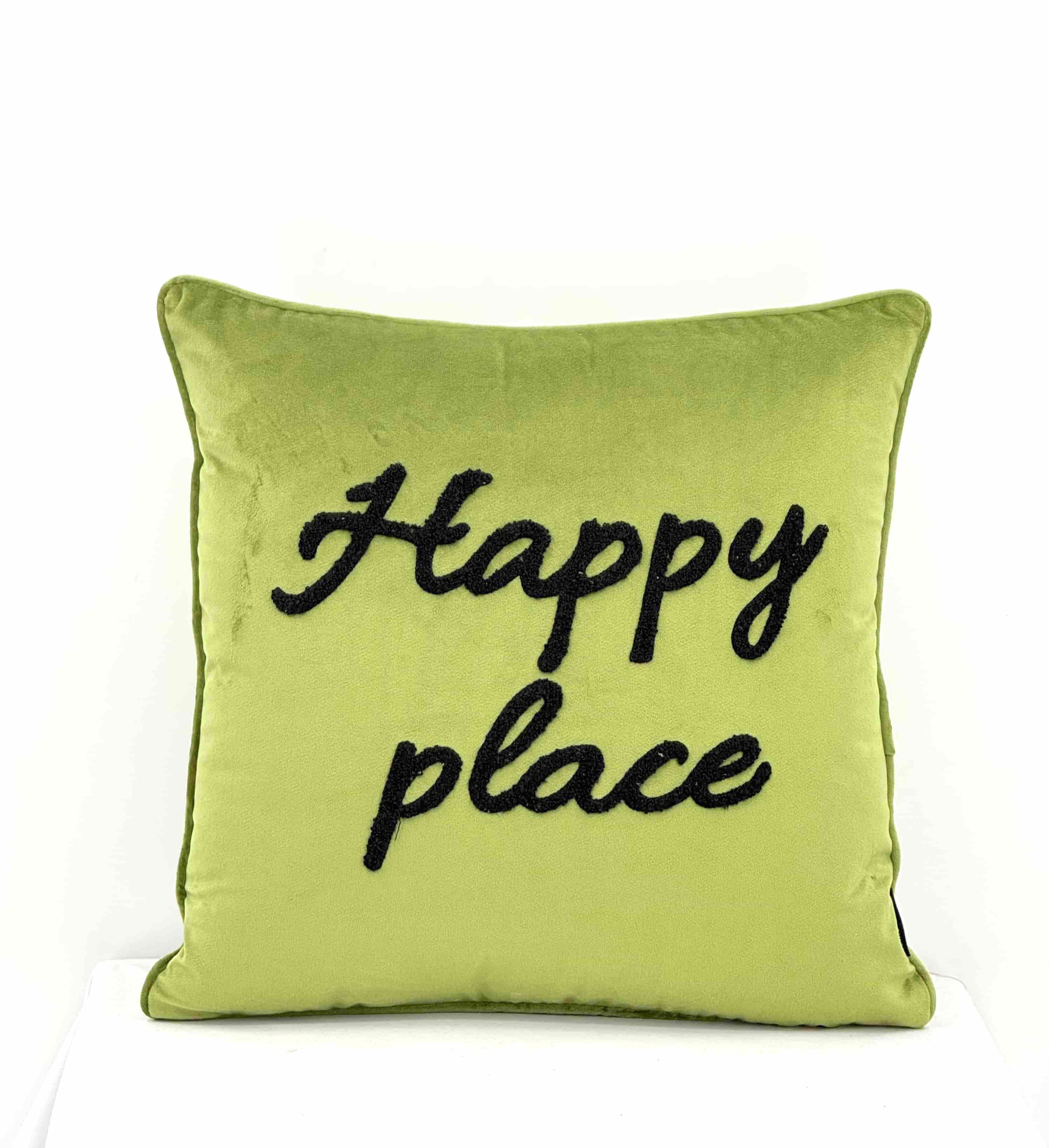 A square lime green velvet throw pillow with the words 'Happy place' embroidered in black script across the front, set against a plain white background.