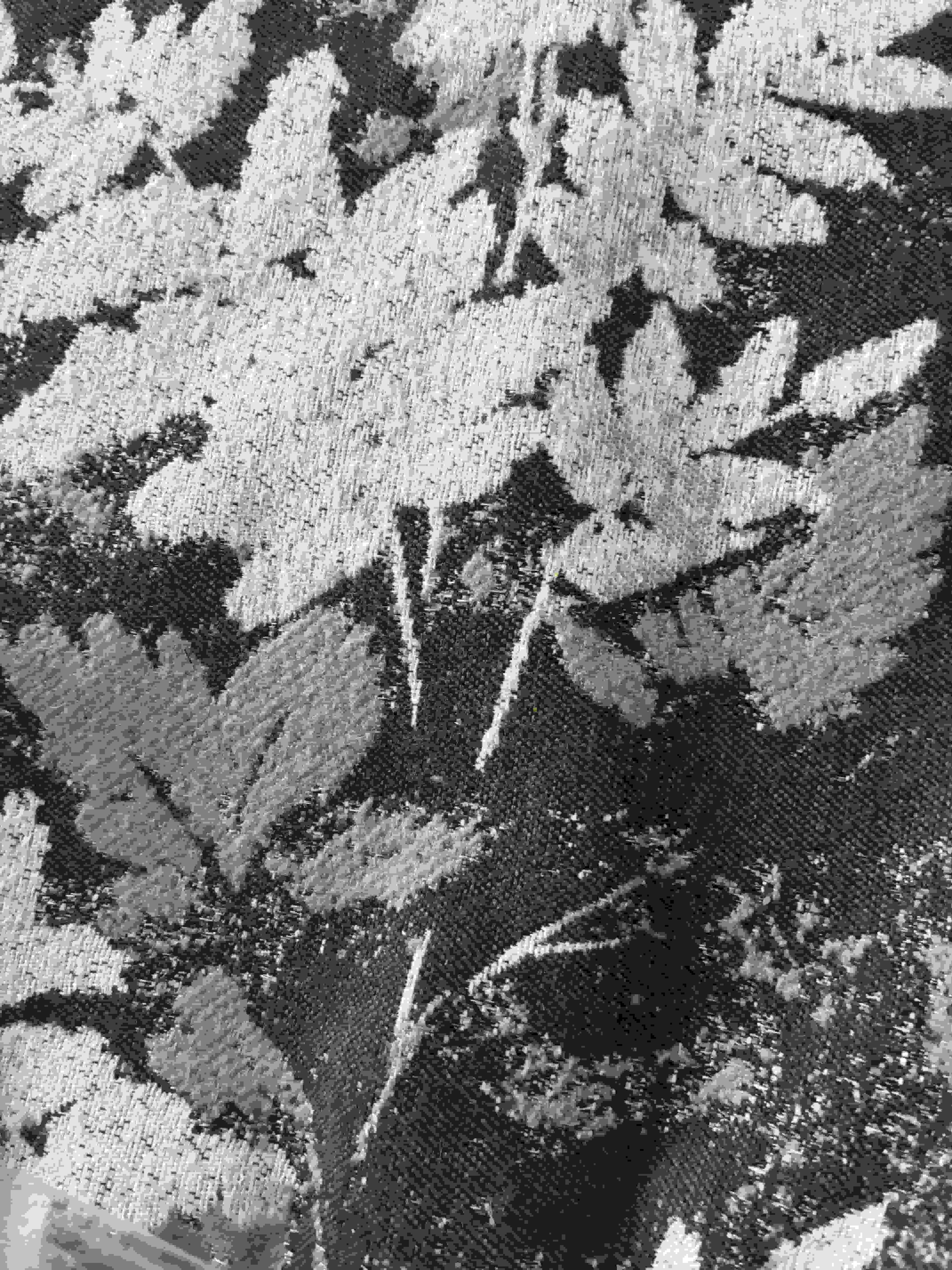 Close-up showing the detailed woven jacquard texture of cream leaves on a dark brown fabric cushion cover.