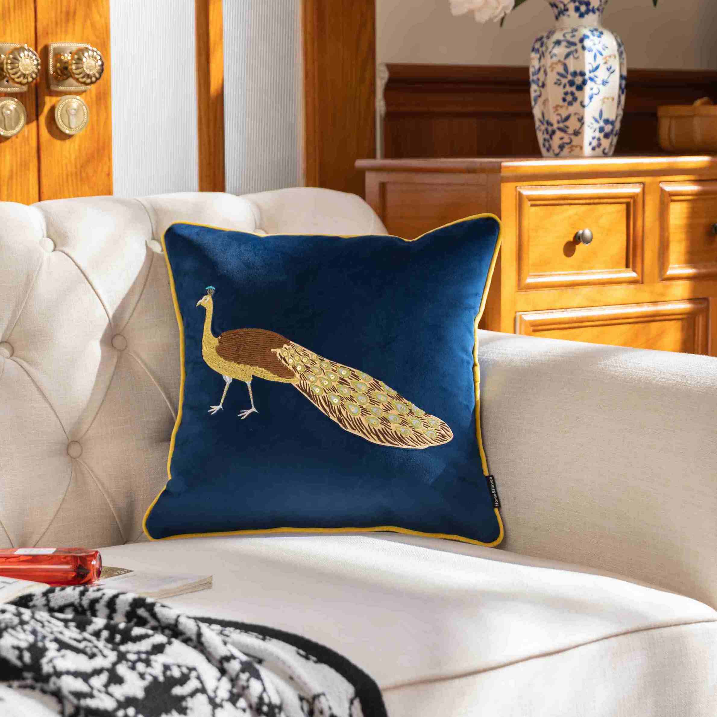 Decorative pillow with peacock design on a white sofa in a living room setting.