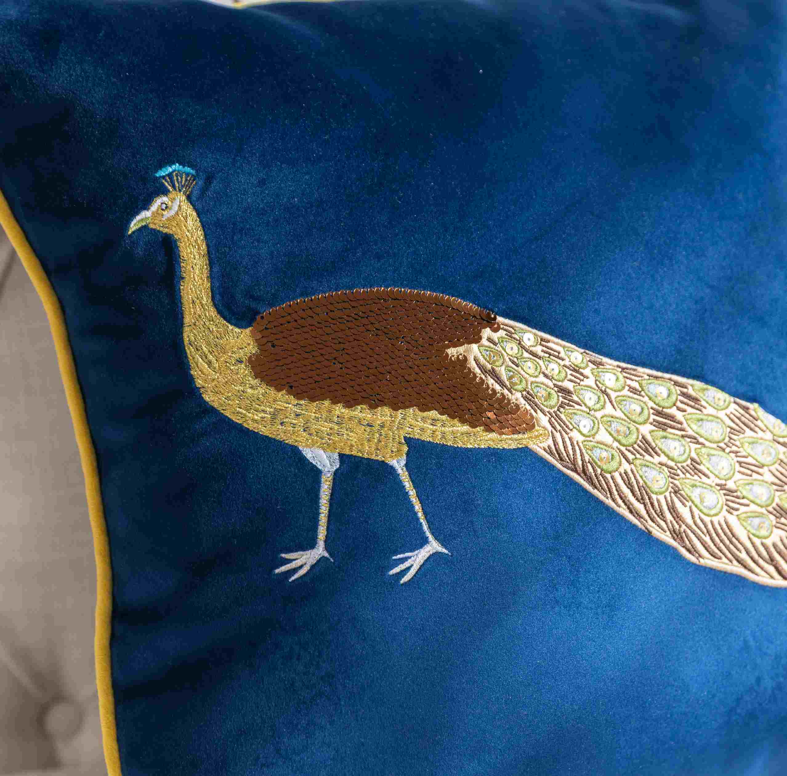 Close-up of peacock embroidery on navy velvet cushion cover