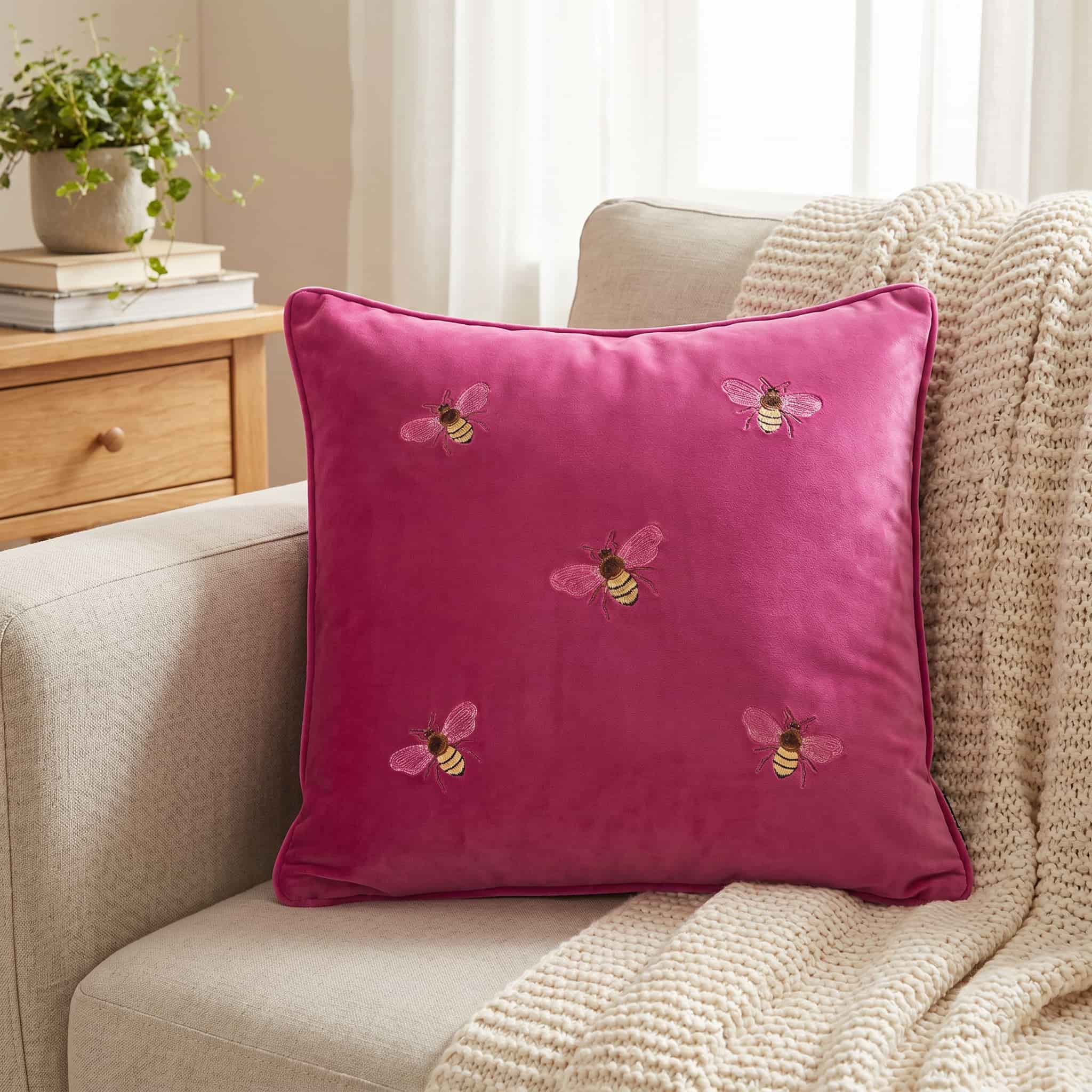 Close up of embroidered honey bee detail on pink velvet cushion cover