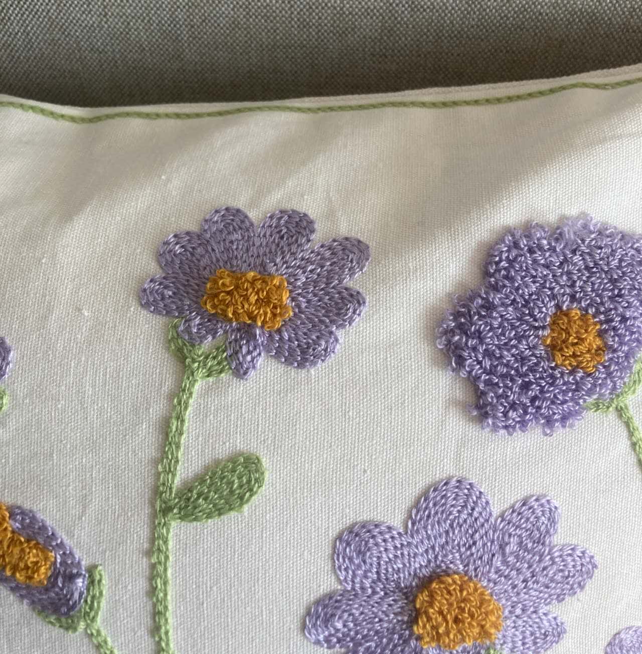 Close-up of purple floral embroidery on cotton cushion cover